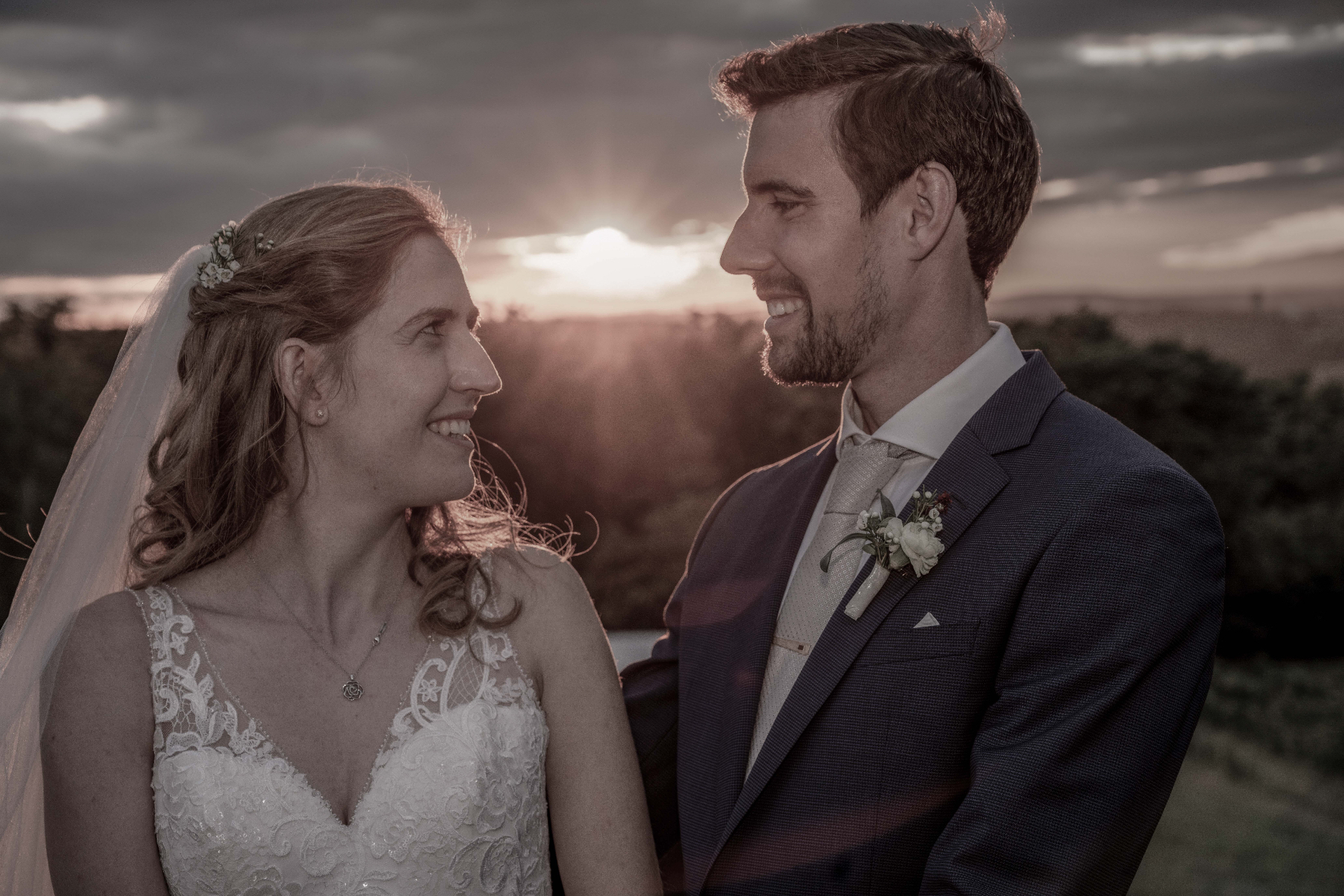 Wedding Stories — a couple at sunset, bride and groom looking at each other