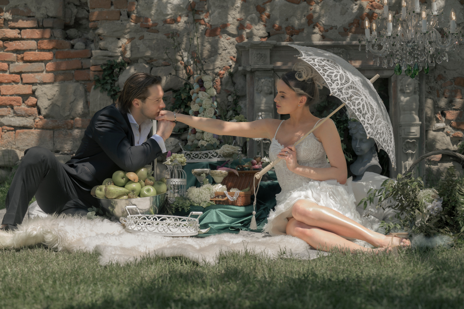 Bride and groom at an intimate garden picnic with a lace parasol