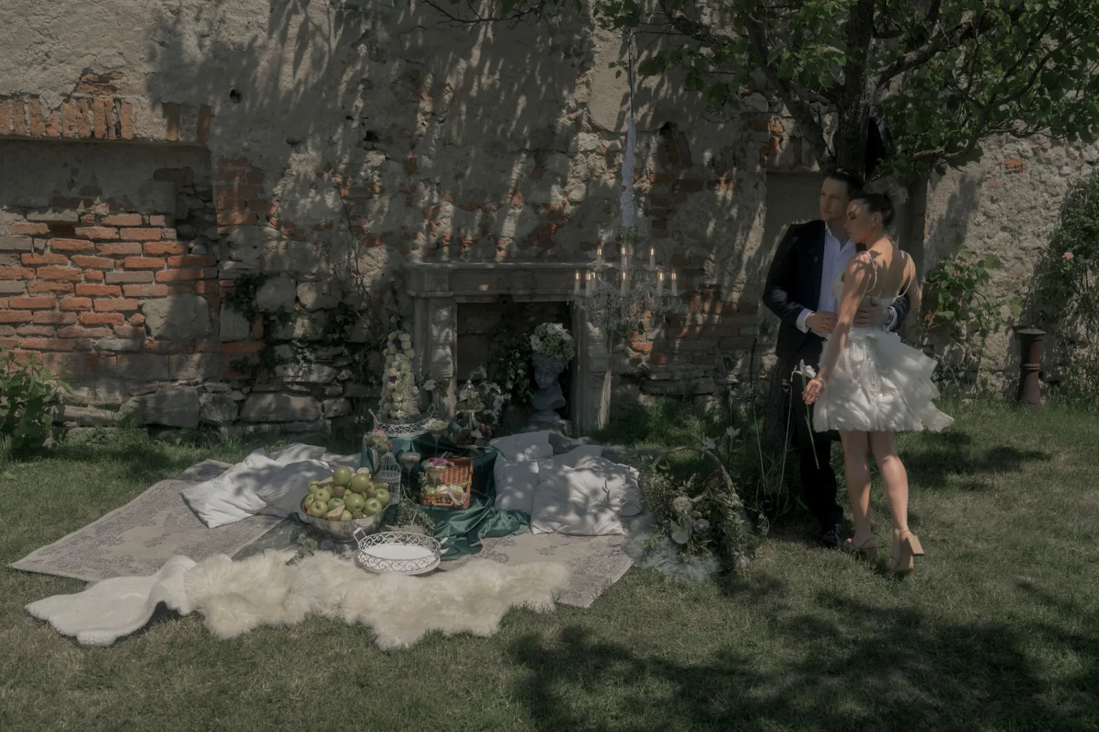Wide editorial wedding scene with bride and groom beneath a tree beside historic Schloss Haggenberg walls.