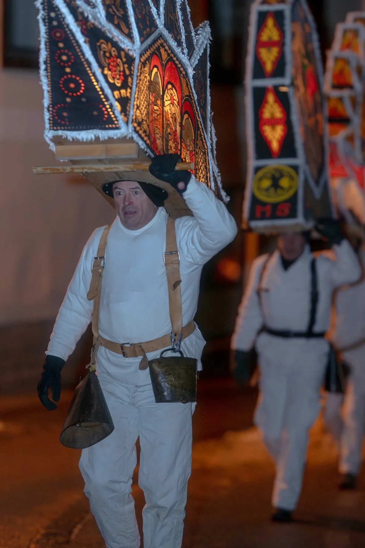 Zwei Glöckler mit Laternenkappen marschieren mit Kuhglocken