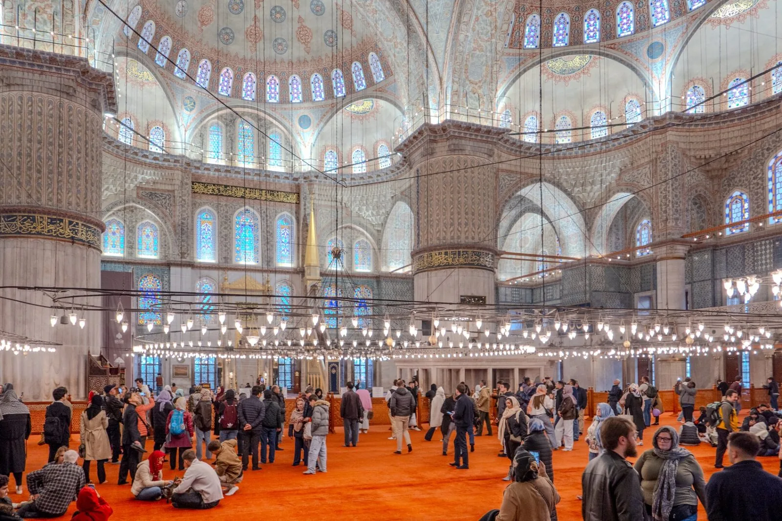 Blue Mosque prayer hall interior with hanging chandeliers and red carpet