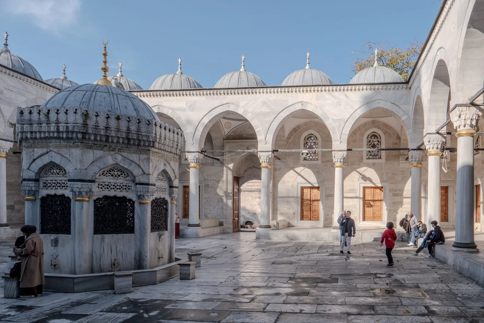 Yeni Valide courtyard ablution fountain with domed roof and visitors in Ottoman architecture setting