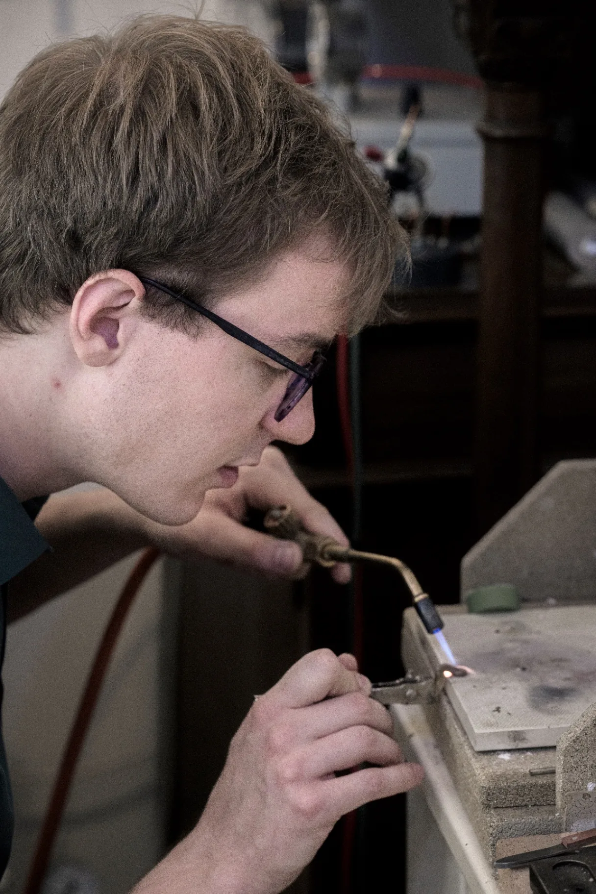 Florian Köck concentrated at the flame, soldering a mechanical part for a woodwind instrument in his Vienna workshop.