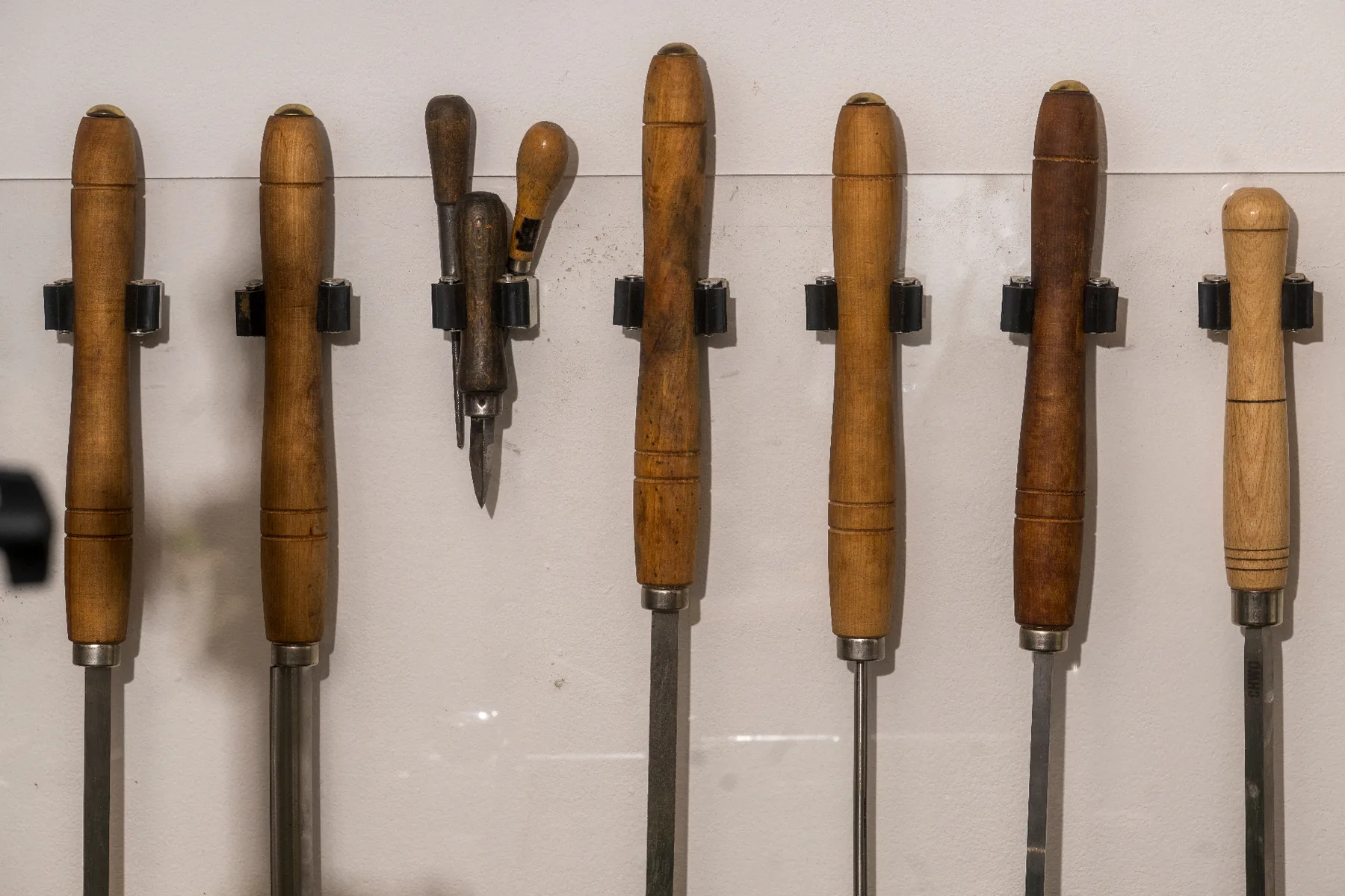 A row of wooden-handled specialist reamers and hand tools mounted on the wall of Florian Köck's Vienna workshop.