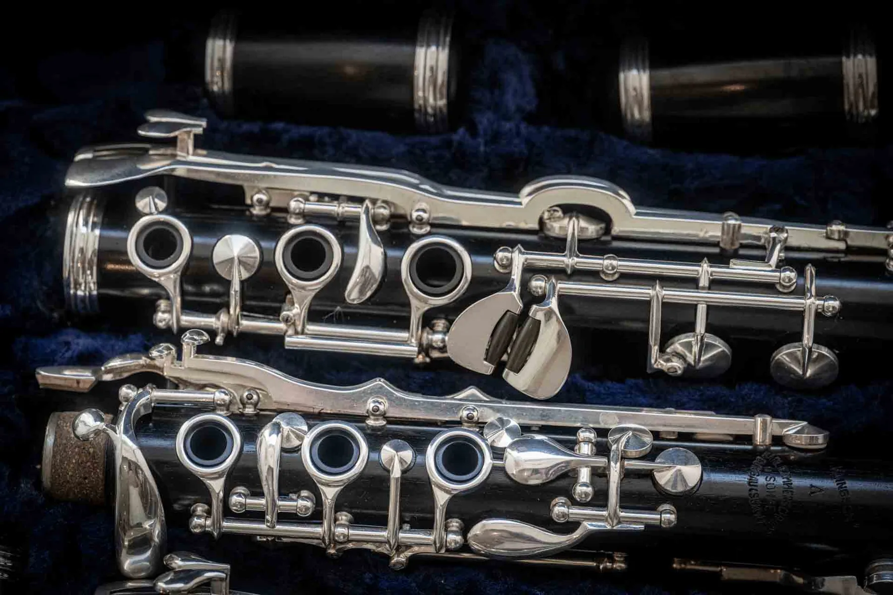 Close detail of a Buffet Crampon clarinet with silver keys resting on deep blue velvet — chapter opening image.