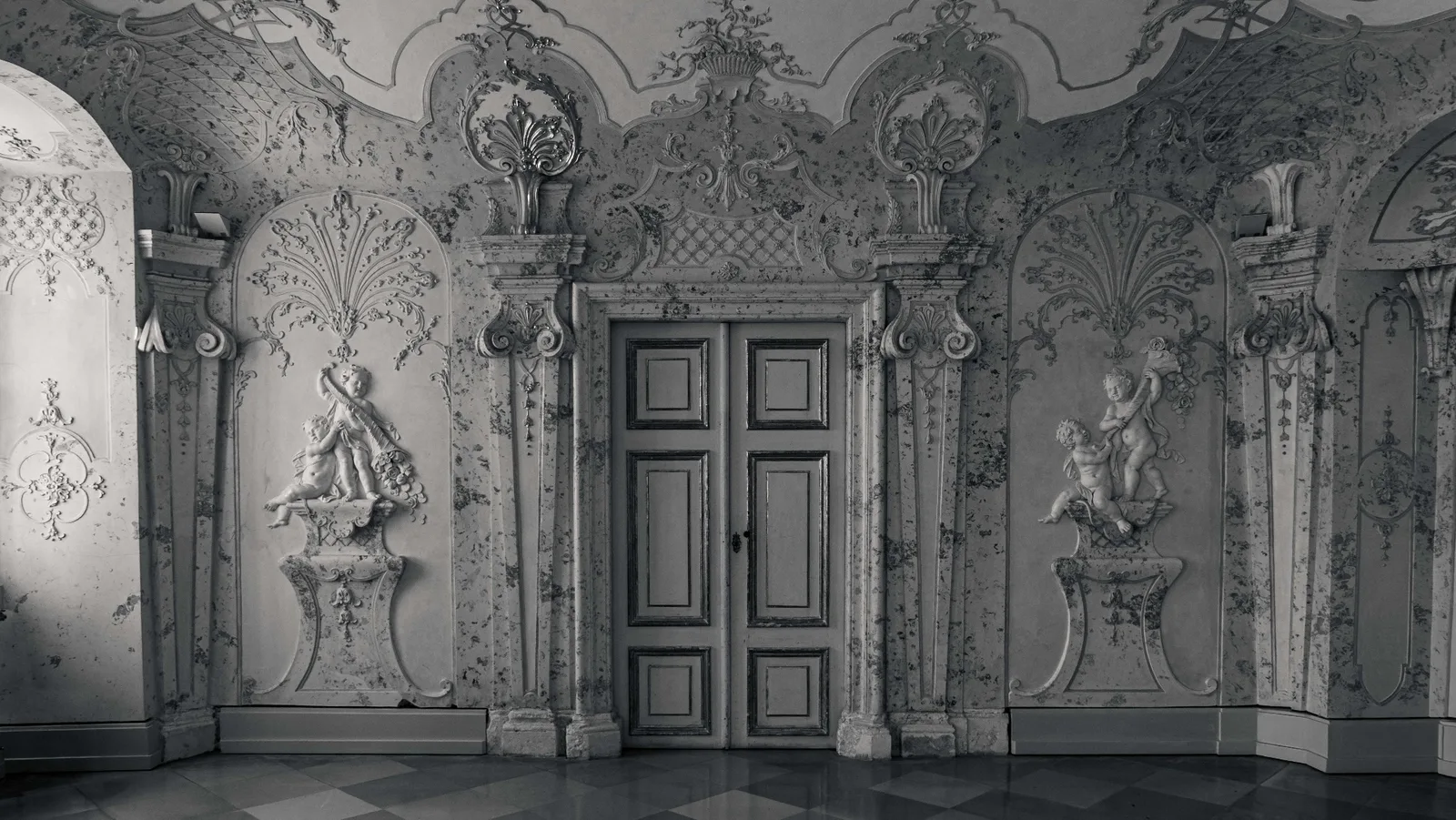 Baroque rococo interior — ornate stucco ceiling with cherub sculptures and paneled door, Schloss Hof by Peter Scholz