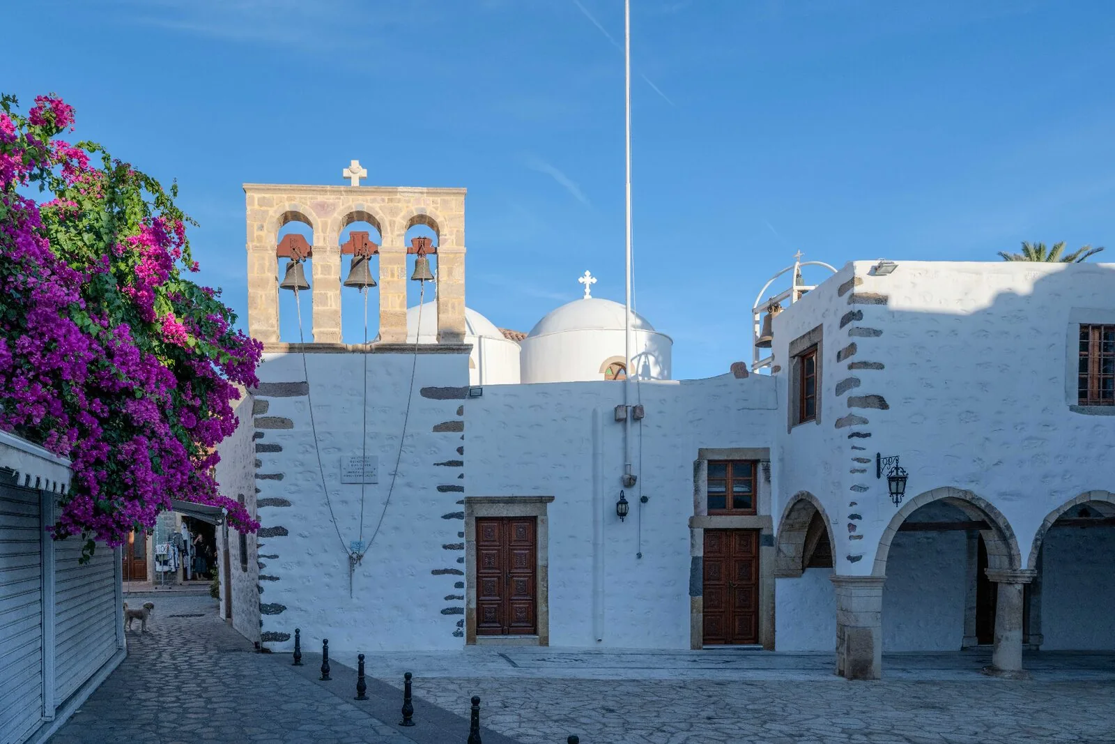 White Orthodox church with triple bell tower and bougainvillea