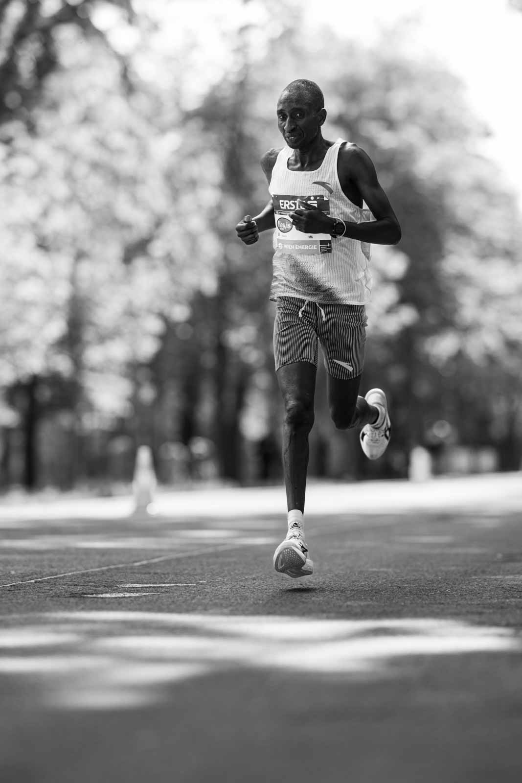 Solitary elite marathon runner airborne on the Prater Hauptallee — black and white fine art photography by schopho