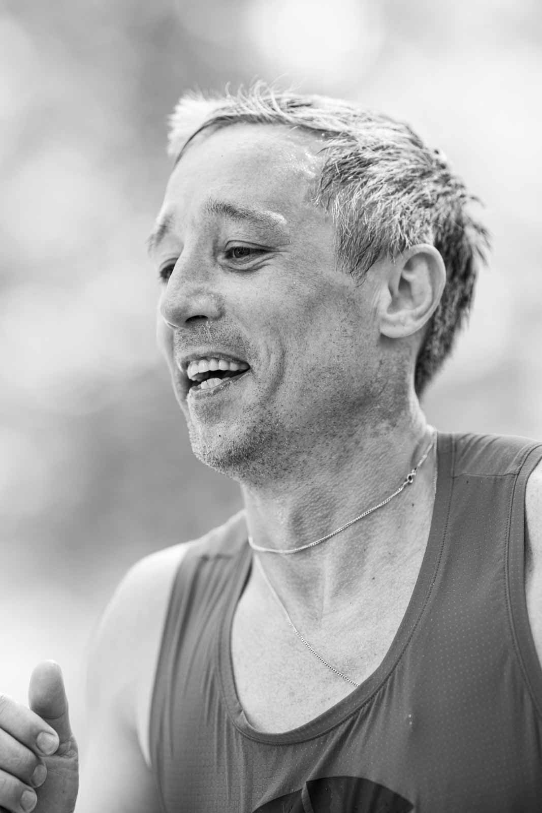 Smiling marathon runner after crossing the finish line — black and white portrait photography by schopho