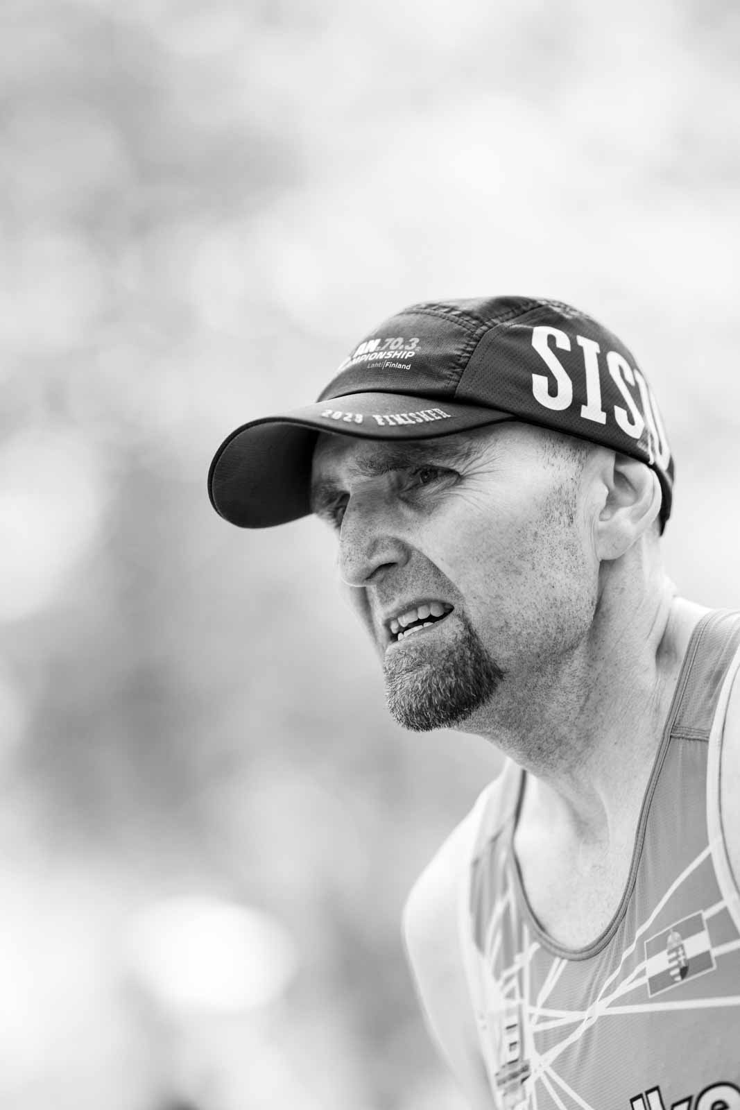 Intense portrait of a marathon runner with SISU cap at the Vienna City Marathon — black and white photography by Peter Scholz