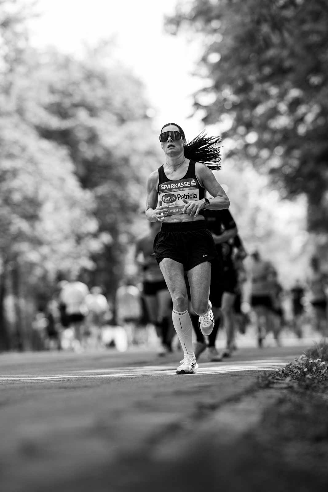 Female marathon runner Patricia running head-on through the Prater Hauptallee — black and white fine art photography by schopho