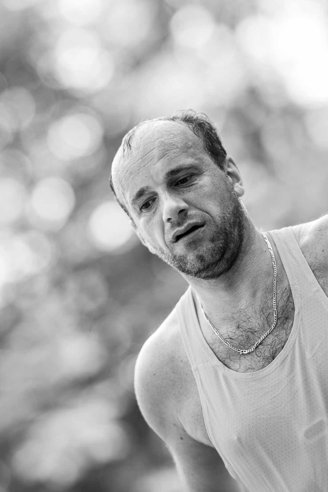 Intimate portrait of an exhausted marathon runner with silver chain after the race — black and white fine art photography by schopho