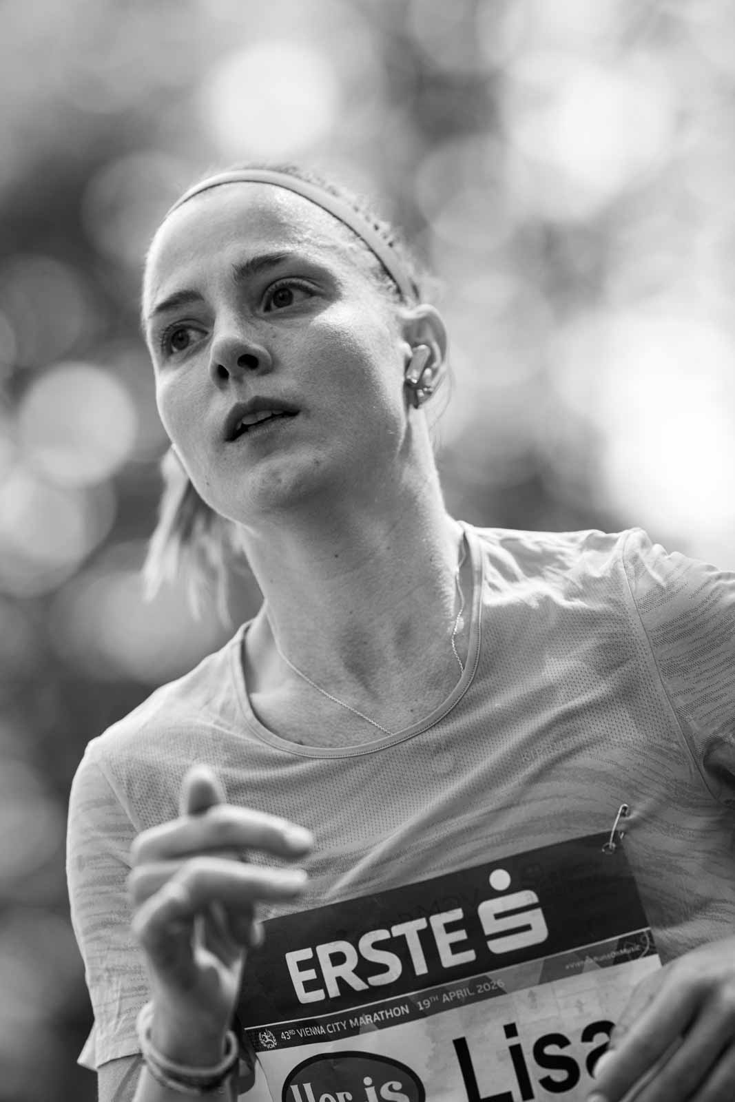 Focused female marathon runner Lisa with earphones at the Vienna City Marathon — black and white portrait photography by schopho