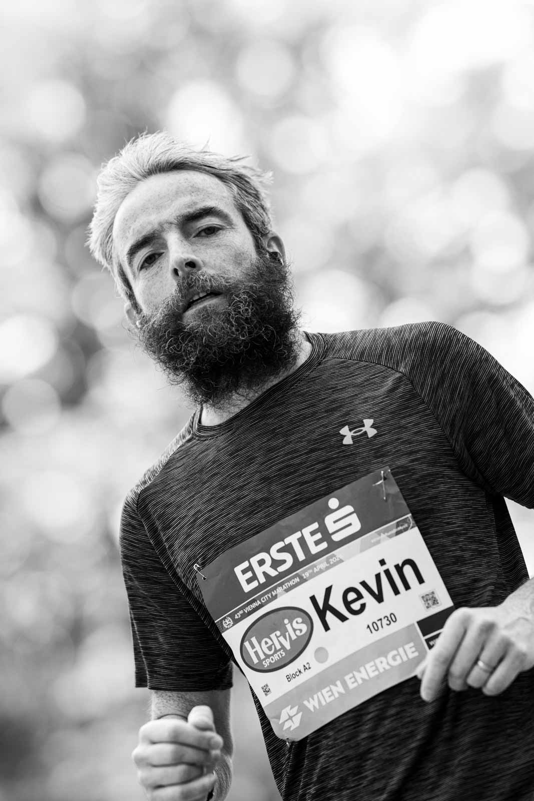 Marathon runner Kevin with full beard and race bib at the Vienna City Marathon — black and white portrait photography by schopho