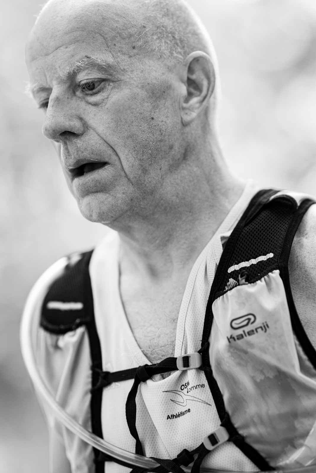 Senior marathon runner with Kalenji vest and hydration system — black and white fine art portrait photography by schopho