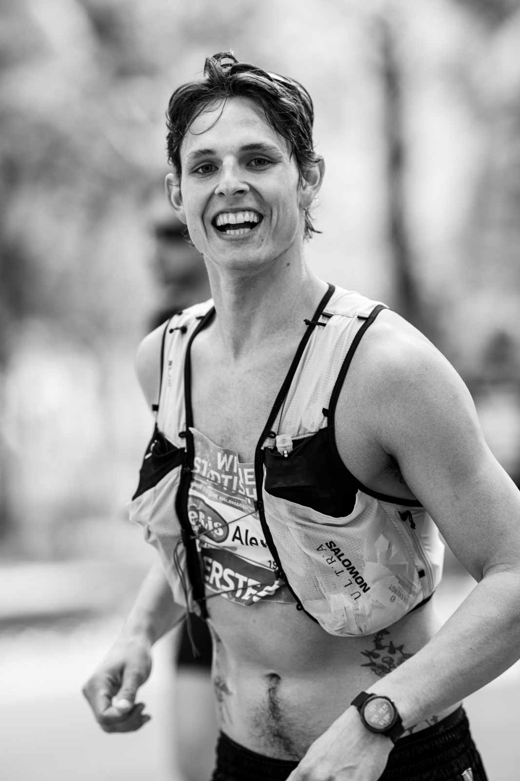 Smiling marathon runner Alex with Salomon hydration vest after the race — black and white editorial photography by schopho
