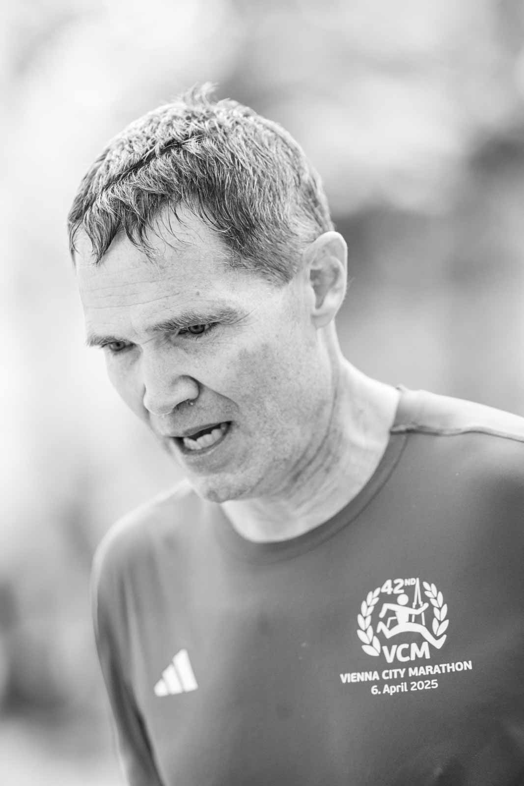 Focused marathon runner with 42nd VCM finisher shirt at the Vienna City Marathon — black and white fine art photography by schopho