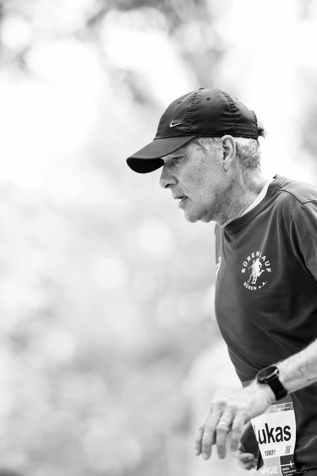 Senior marathon runner Lukas with Bürenlauf shirt and Nike cap in the Vienna Prater — black and white fine art photography by schopho