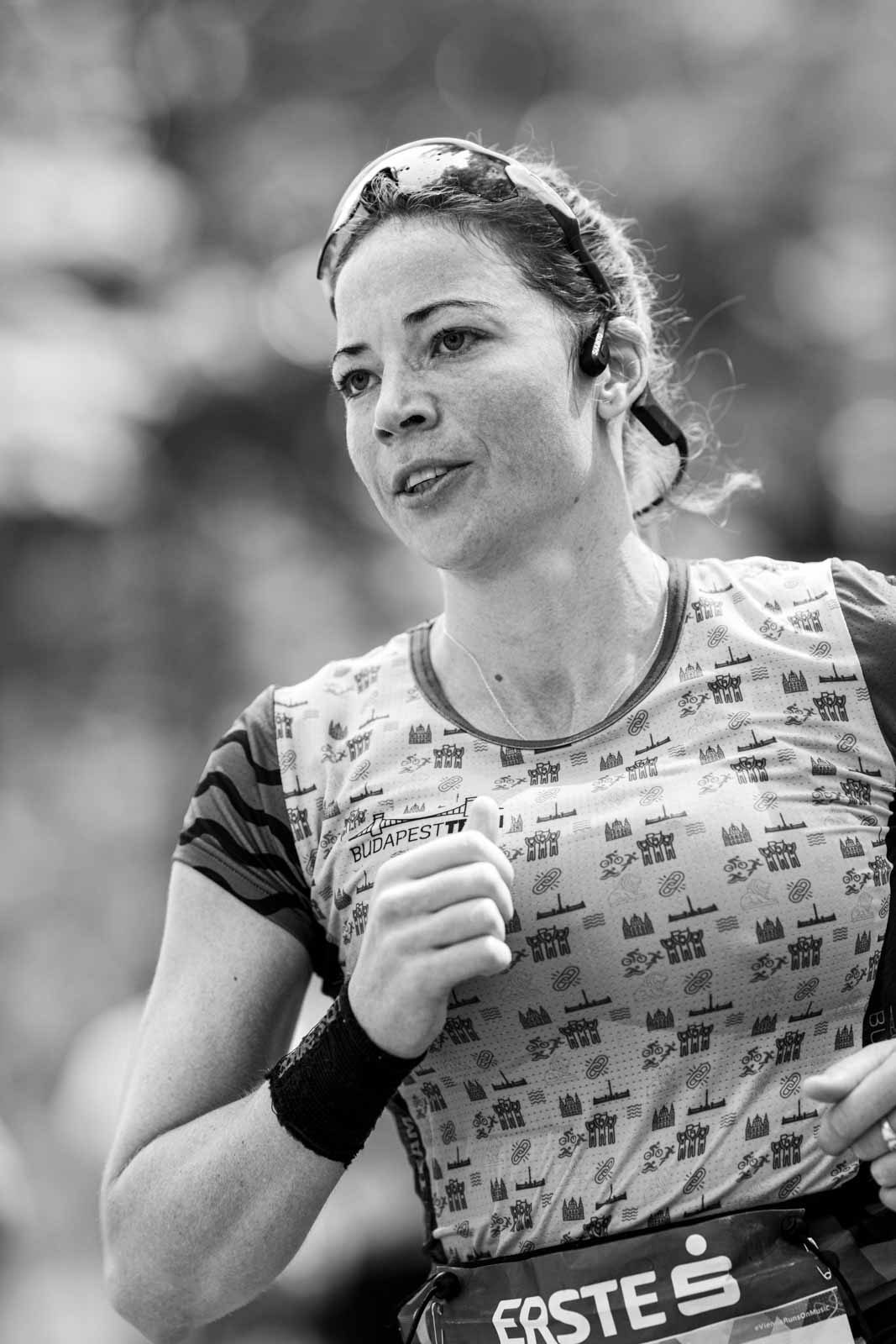 Female marathon runner with Budapest singlet and bone-conduction headphones — black and white portrait photography by Peter Scholz, schopho
