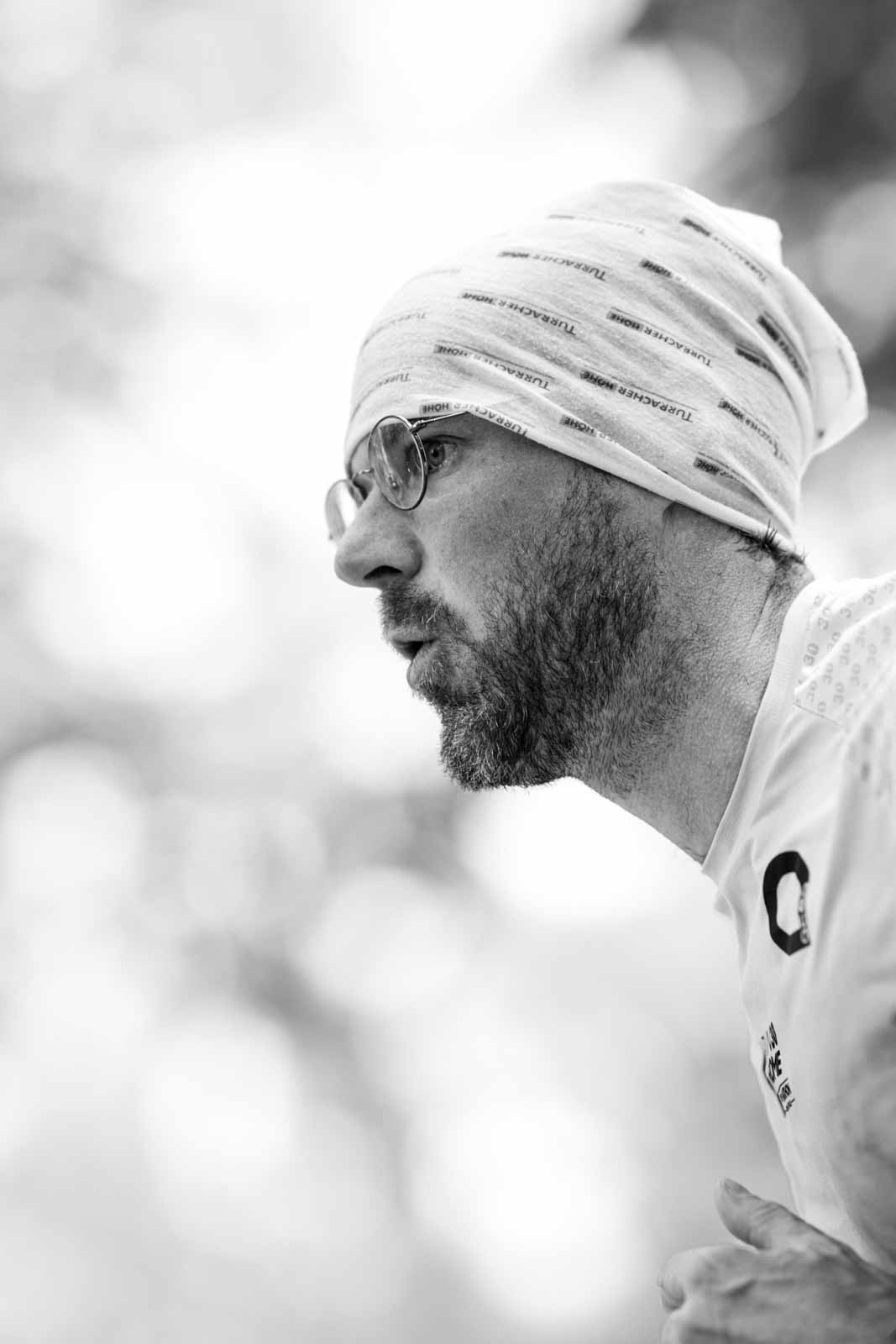 Profile portrait of a marathon runner with Turracher Höhe beanie and round glasses — black and white fine art photography by Peter Scholz