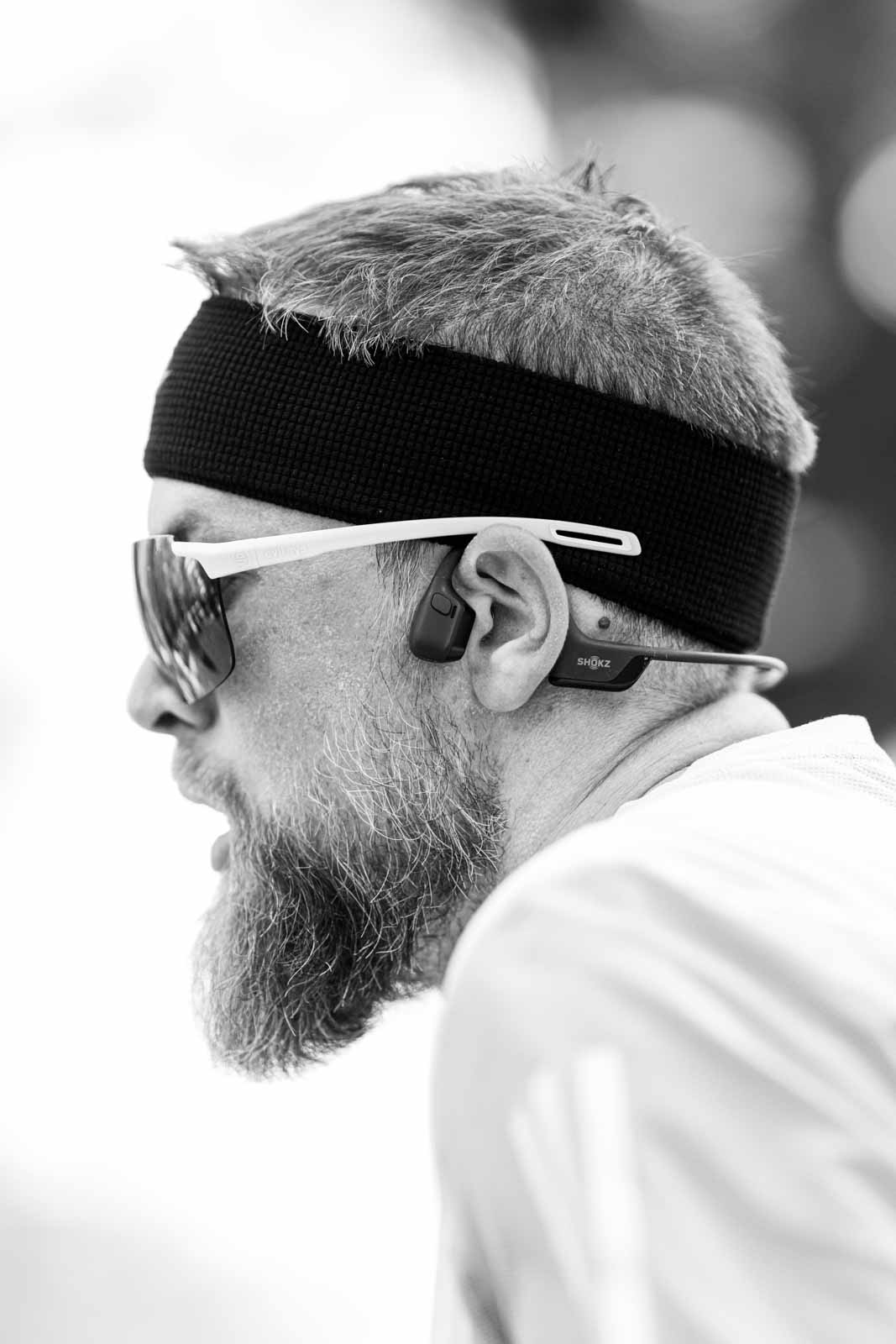 Profile portrait of a bearded marathon runner with Shokz headphones and headband — black and white fine art photography by Peter Scholz