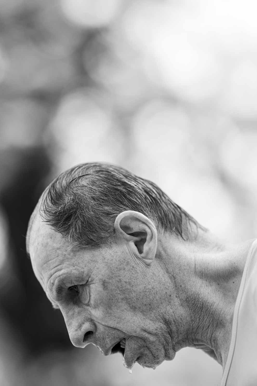 Intimate profile portrait of an exhausted senior marathon runner at kilometer 35 — black and white fine art photography by schopho
