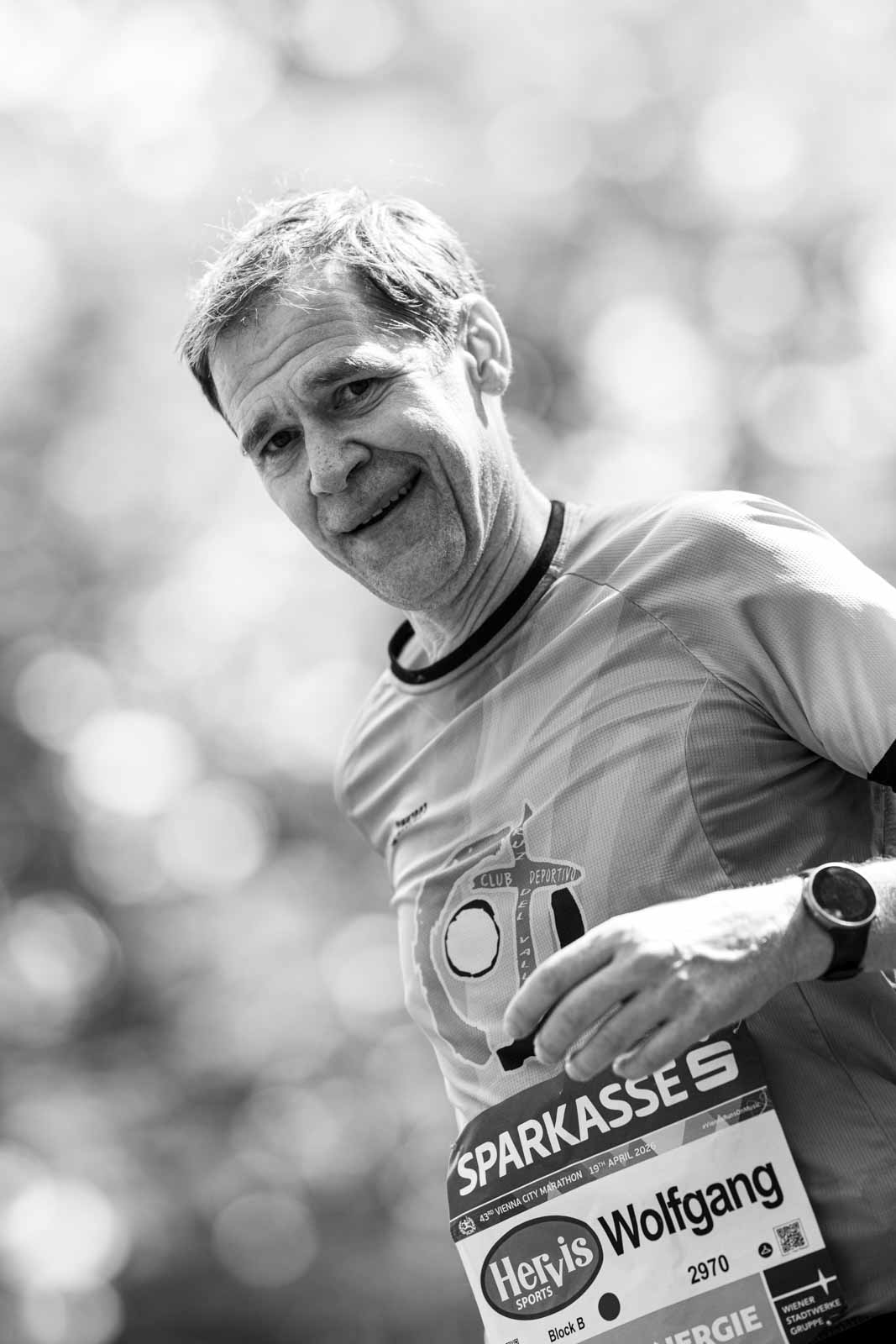Smiling senior marathon runner Wolfgang with Club Deportivo del Valle shirt at the Vienna City Marathon — black and white portrait photography by schopho